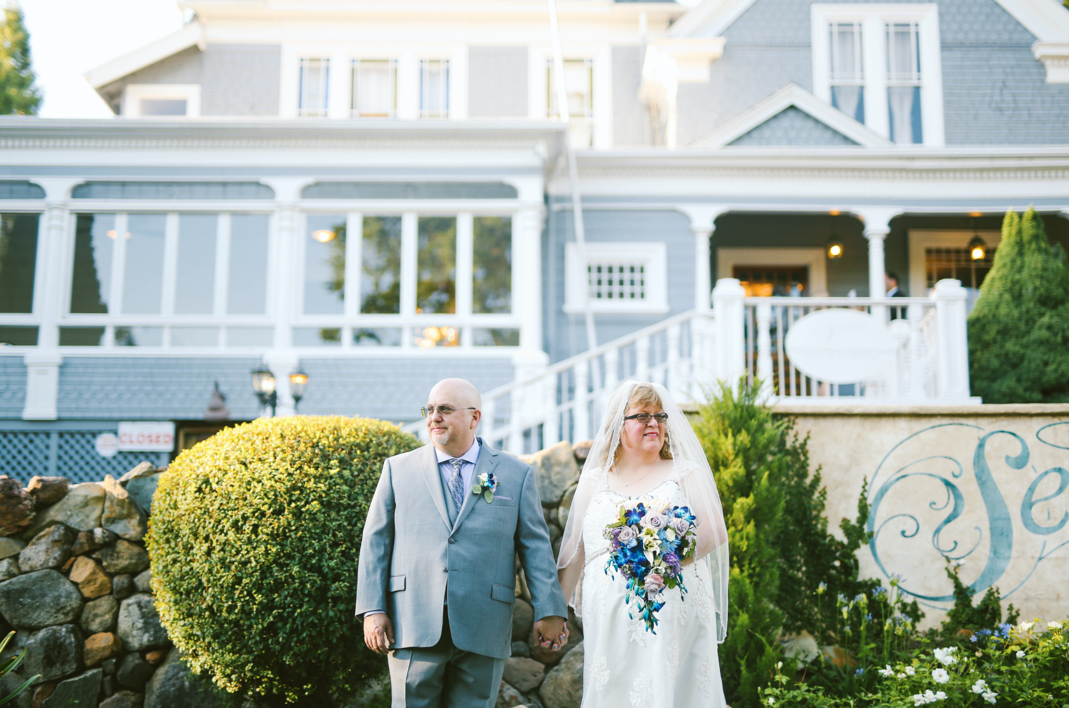 Bride & Groom in front of cute blue home